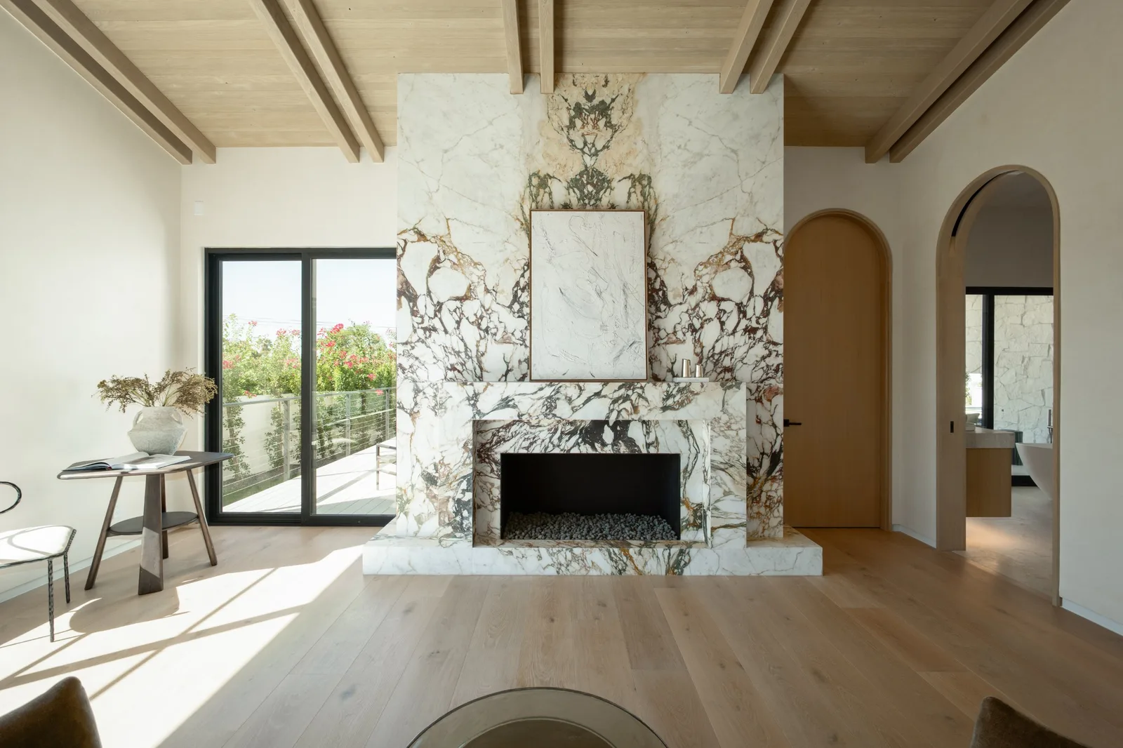 Primary suite sitting room with marble fireplace and beamed ceiling